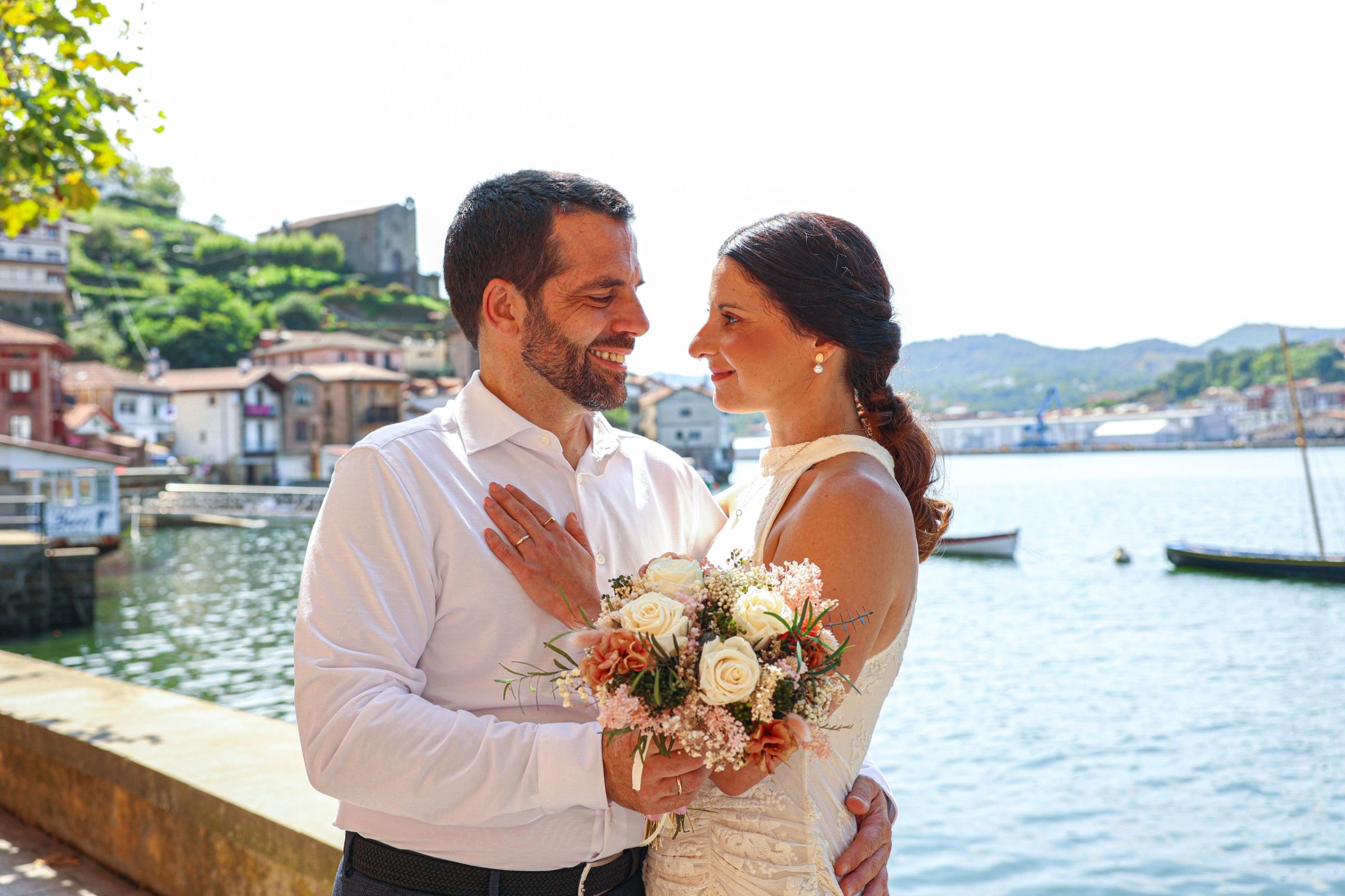 Novios abrazados junto a la bahía de Pasai Donibane el día de su boda